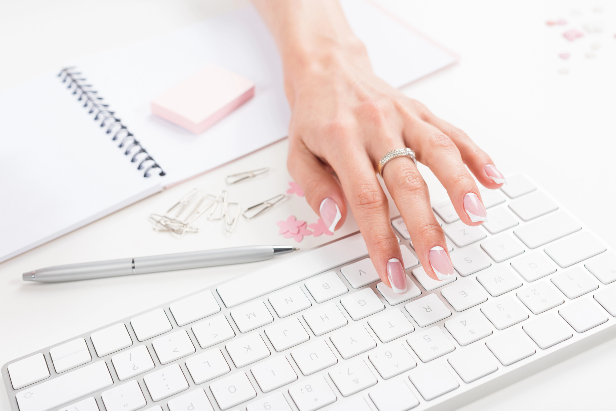 Main élégante sur clavier — carnet, stylo et détails raffinés sur bureau épuré