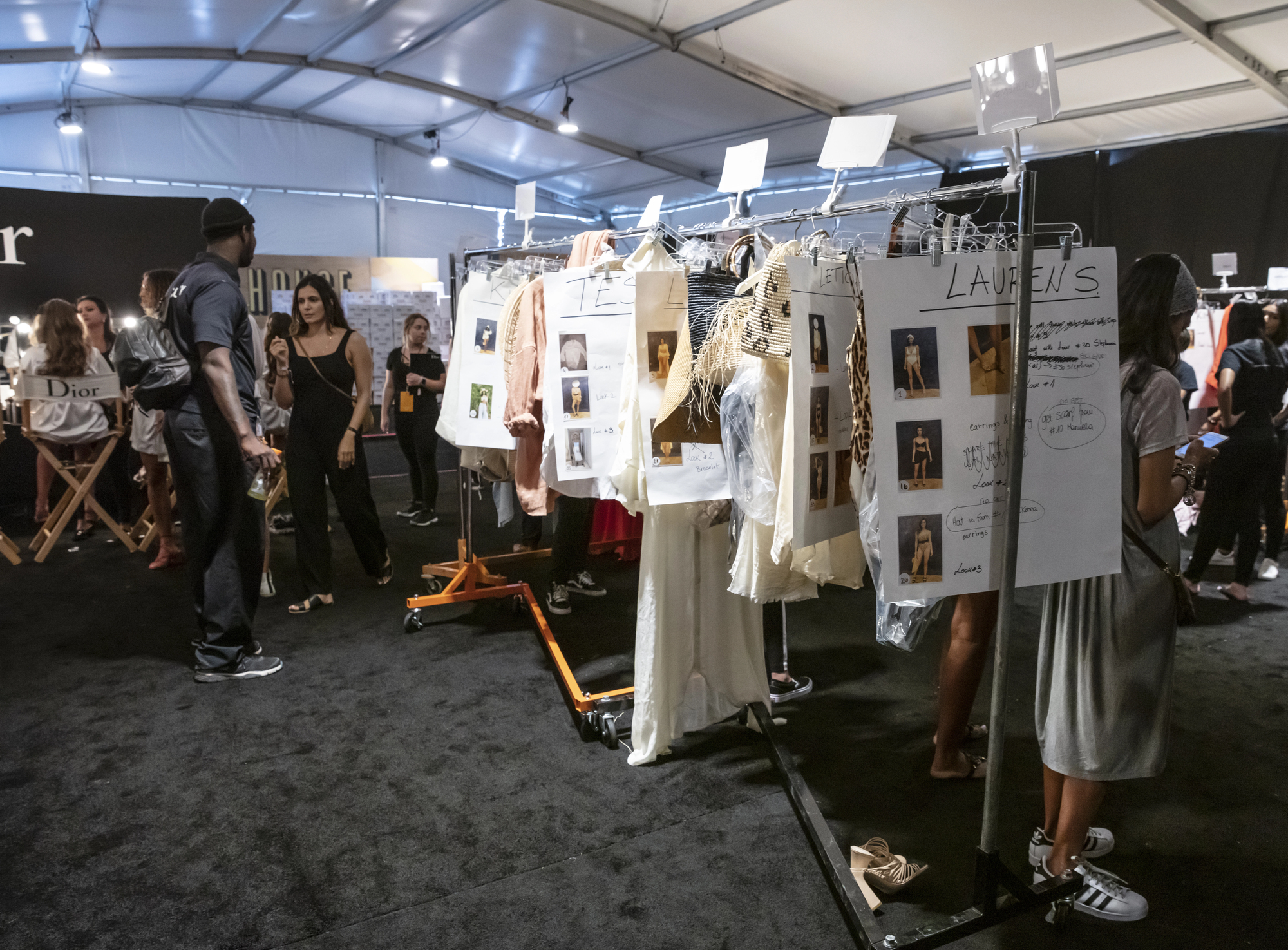 Coulisses d'un défilé Dior — portants de vêtements, équipe de production en action