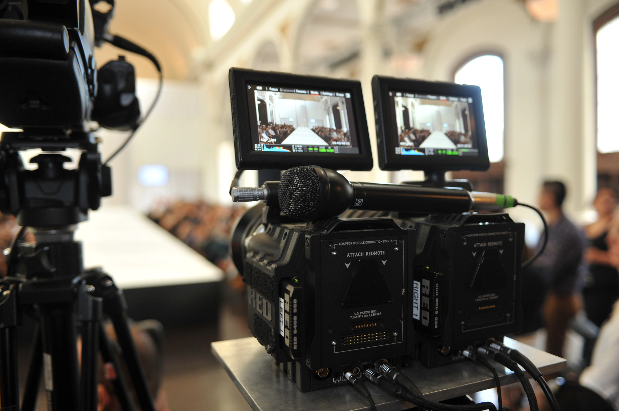 Caméra professionnelle RED sur un tournage de défilé — public et podium en arrière-plan flou