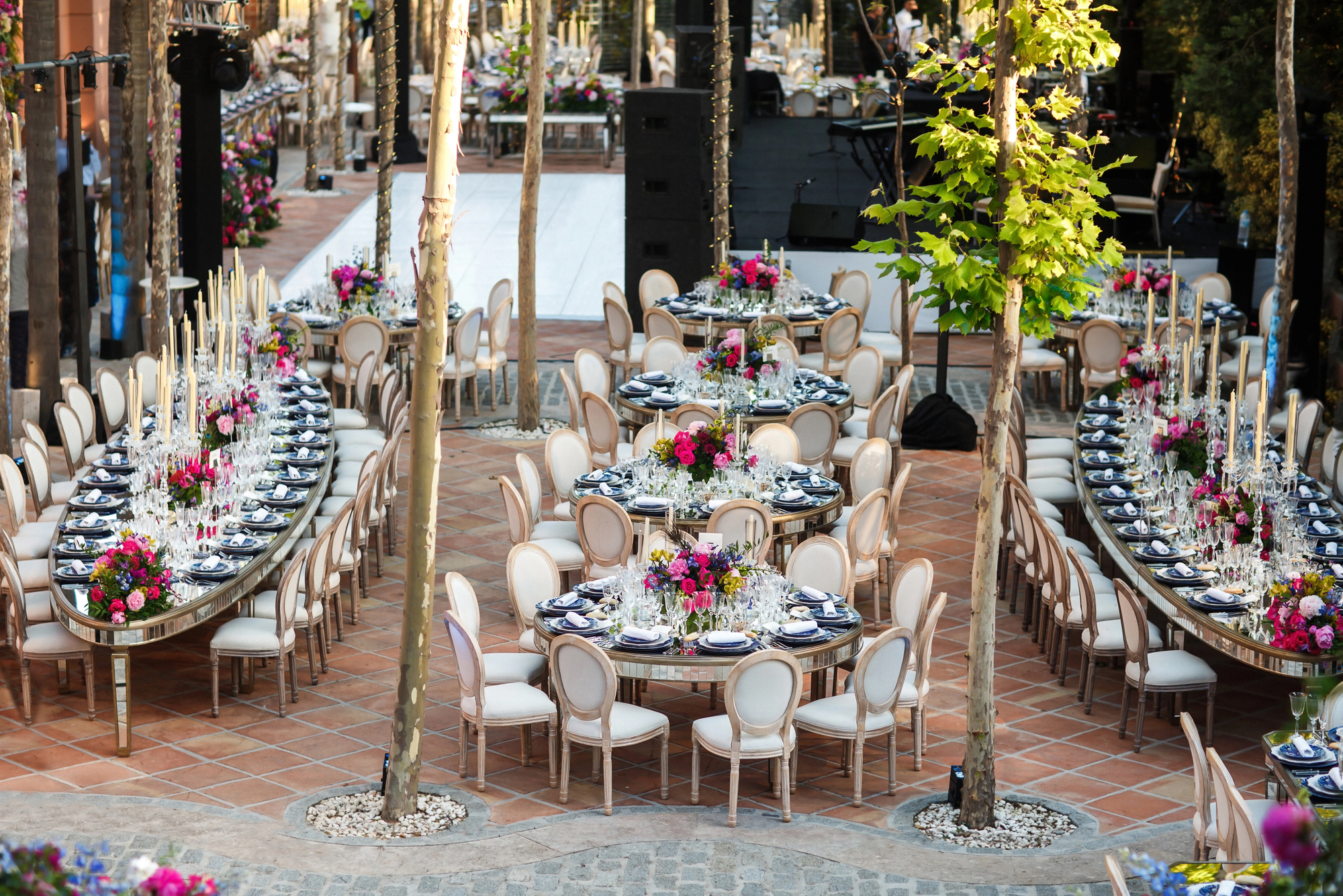 Dîner de gala en plein air — tables dressées avec soin parmi les arbres, lumière dorée